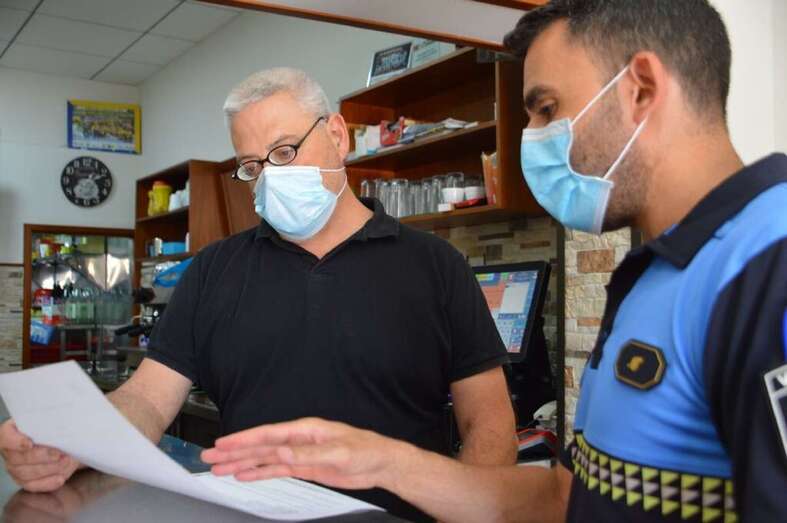 Un policía local de Valsequillo entrega el bando a un negocio local/TA.